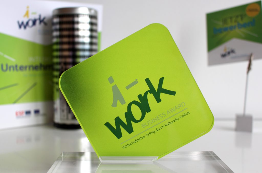 Close-up of the i-work Business Award. Marketing materials in the background.